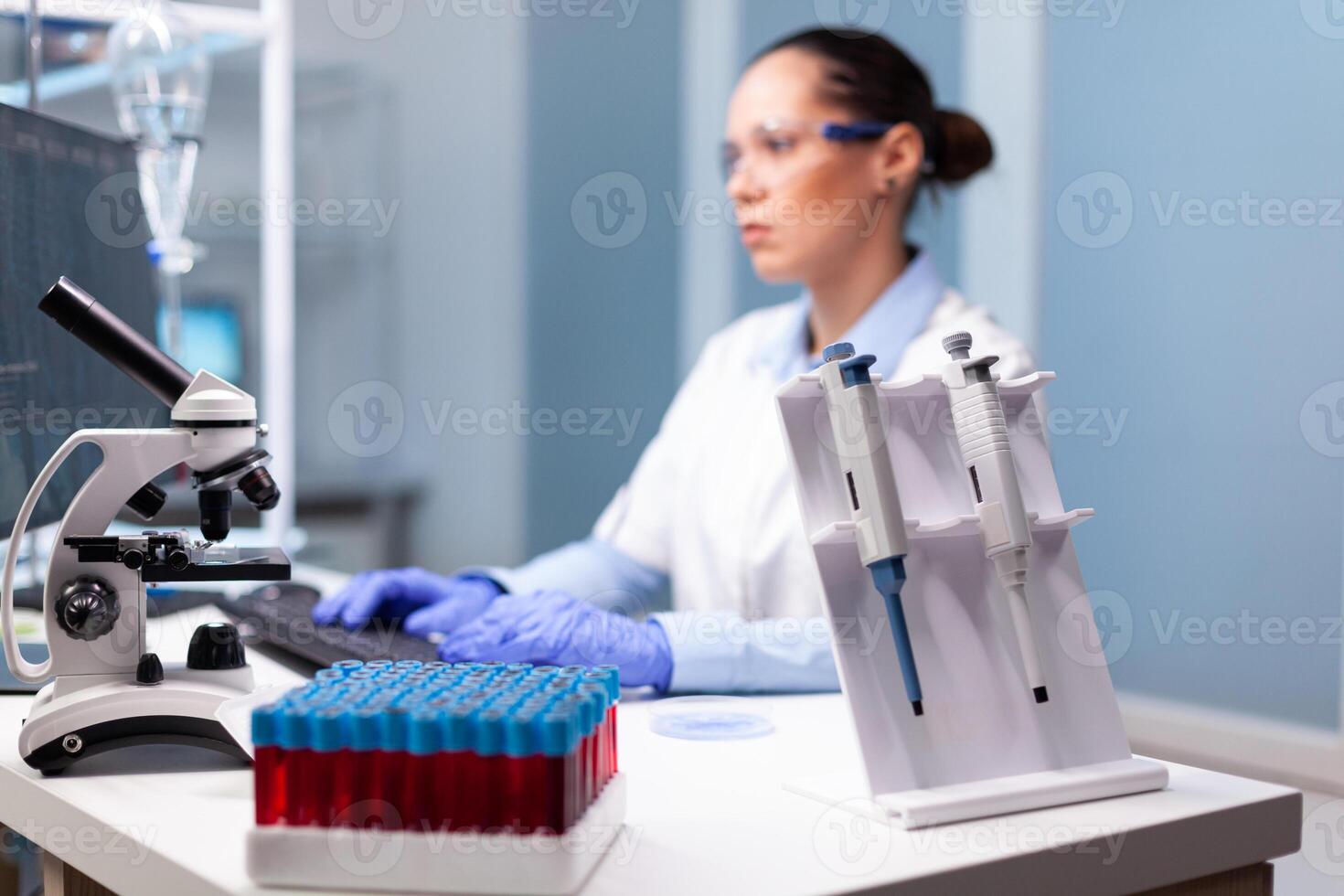 Microbiology scientist typing biochemistry discovery experiment at computer using medical high tech working in pharmacology hospital laboratory.Biology doctor developing virus treatment expetise photo