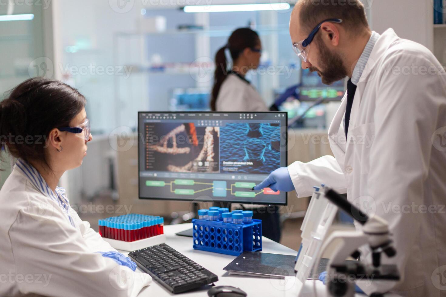 Team of microbiology scientists discussing about vaccine development in modern equipped laboratory. Chemists stuff analysing virus evolution using high tech technology for treatment research. photo