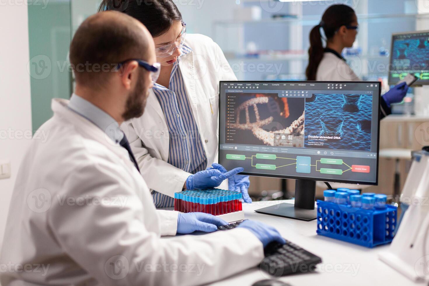 Group of scientists working in modern equipped laboratory pointing on computer desktop. y pointing on computer desktop. Chemists stuff analysing virus evolution using high tech technology for treatment research. photo