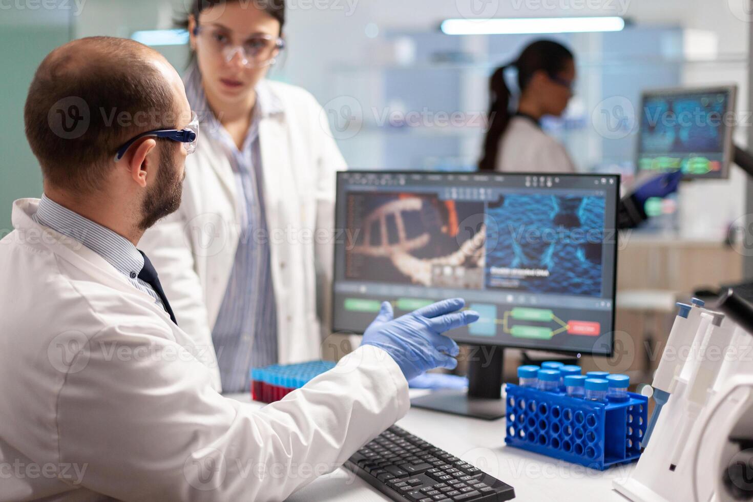 Medical team scientist conducting DNA experiments looking in computer holding test tube with blood sample. Chemists stuff analysing virus evolution using high tech technology for treatment research. photo