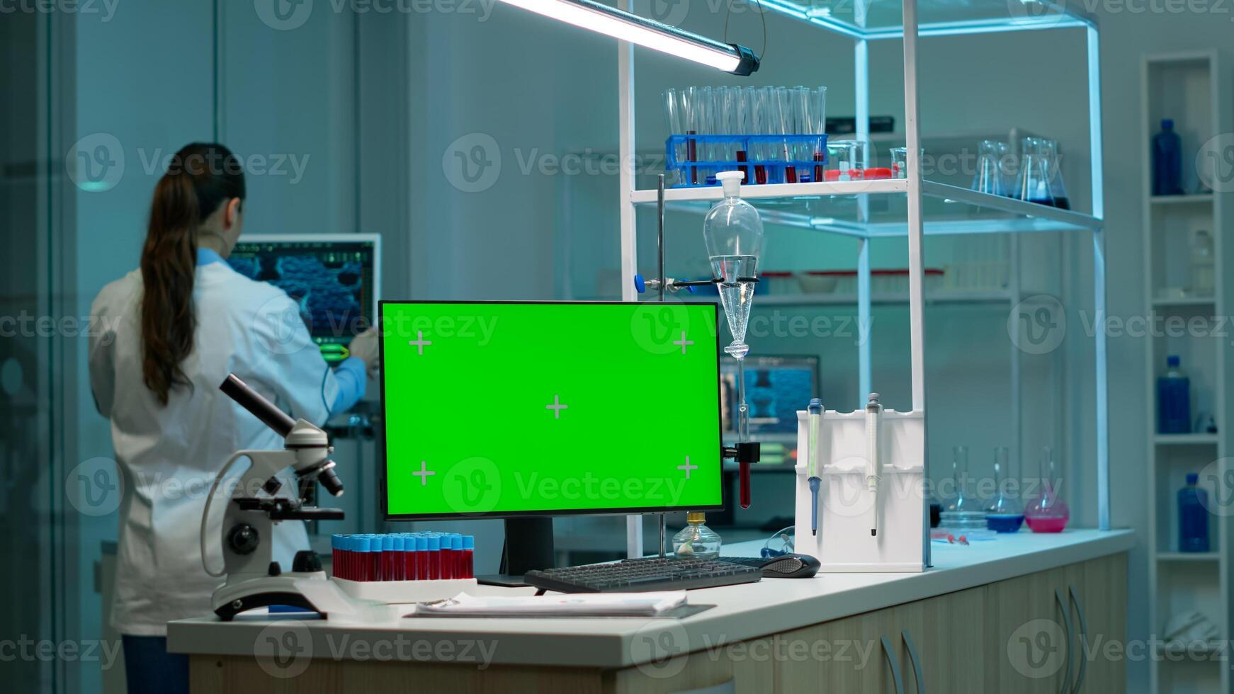 Computer with green screen working in labooratory with mock up monitor, chroma key display while professional engineer testing virus evolution in background. High tech development lab. photo