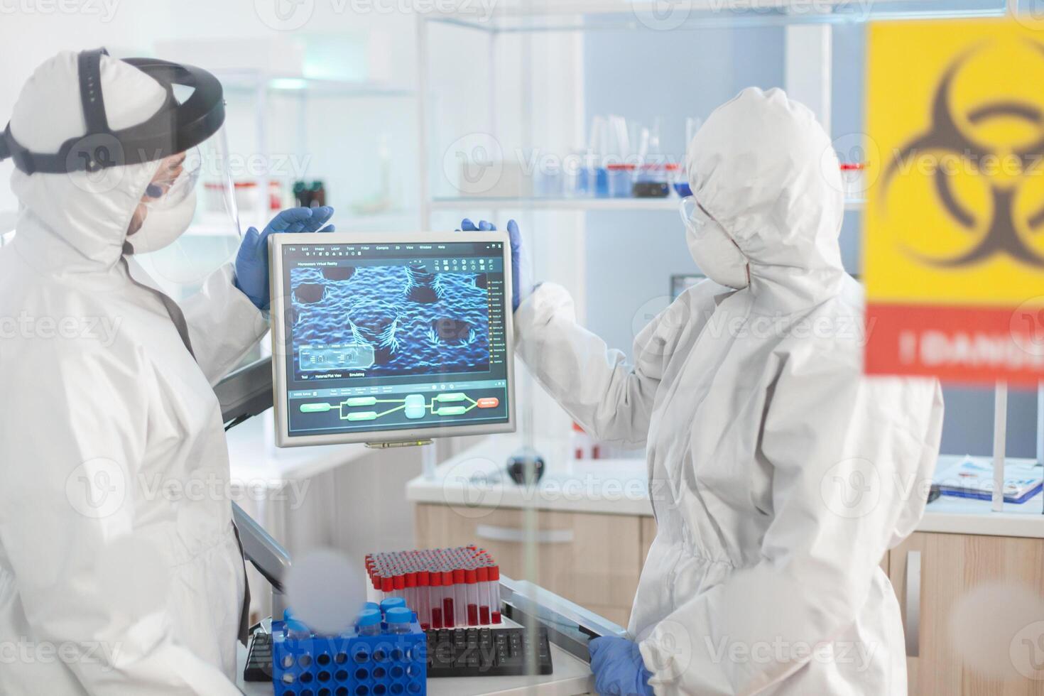 Team of scientist looking at virus evolution standing in lab danger zone dressed in ppe suit. Group of doctors examining vaccine evolution using high tech for diagnosis against covid19. photo
