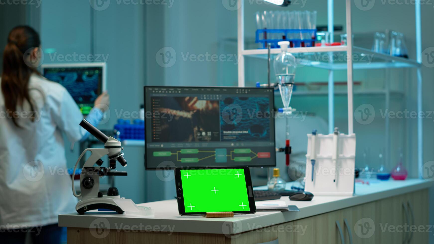 Tablet with green screen working in labooratory with mock up, chroma key display while professional engineer testing virus evolution in background. High tech development lab with blood samples photo