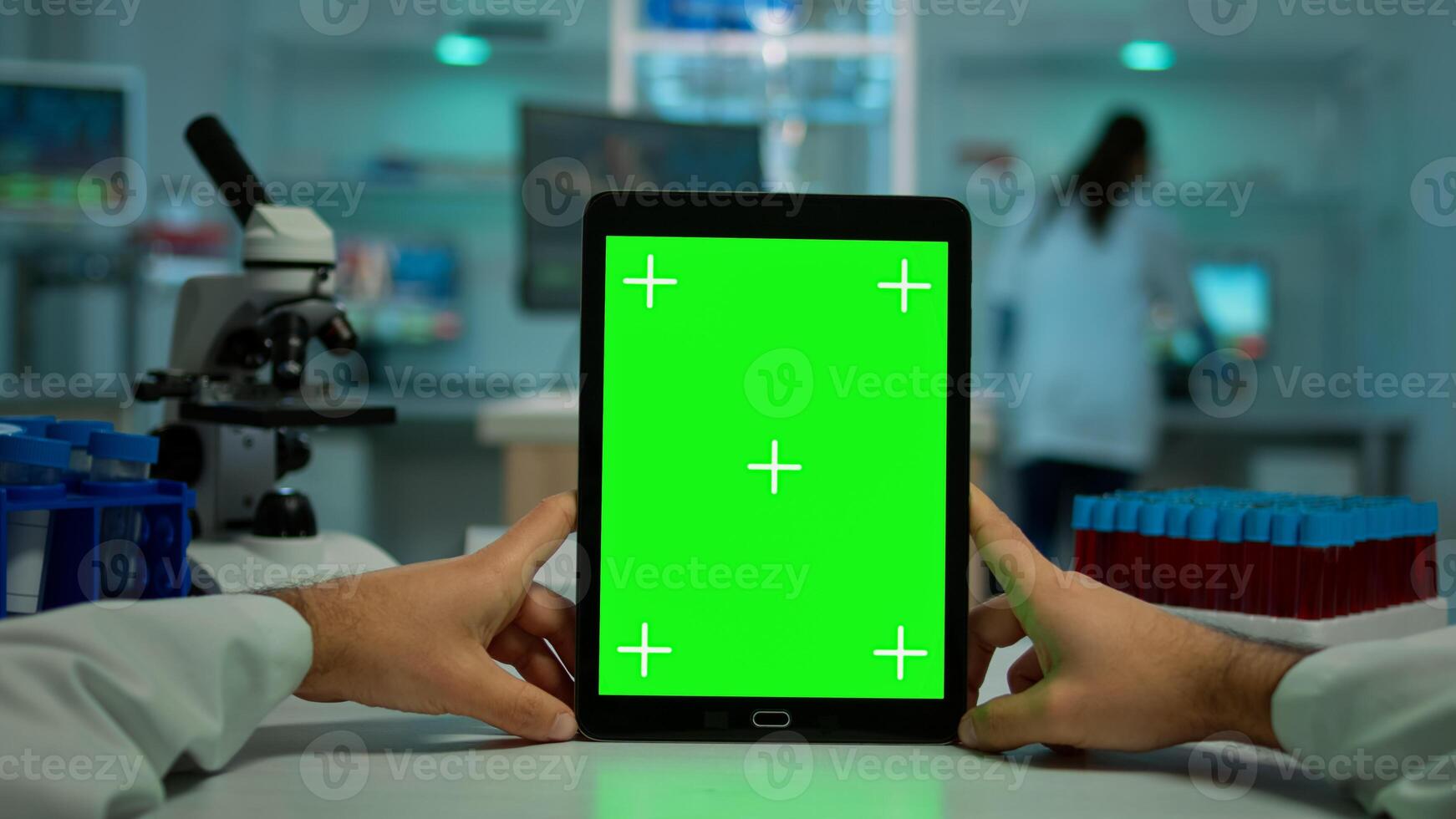 POV shot of chemist using tablet with green screen in biological laboratory. Medical worker wearing white coat in clinic working with notebook with chroma key on isolated display in medical lab photo