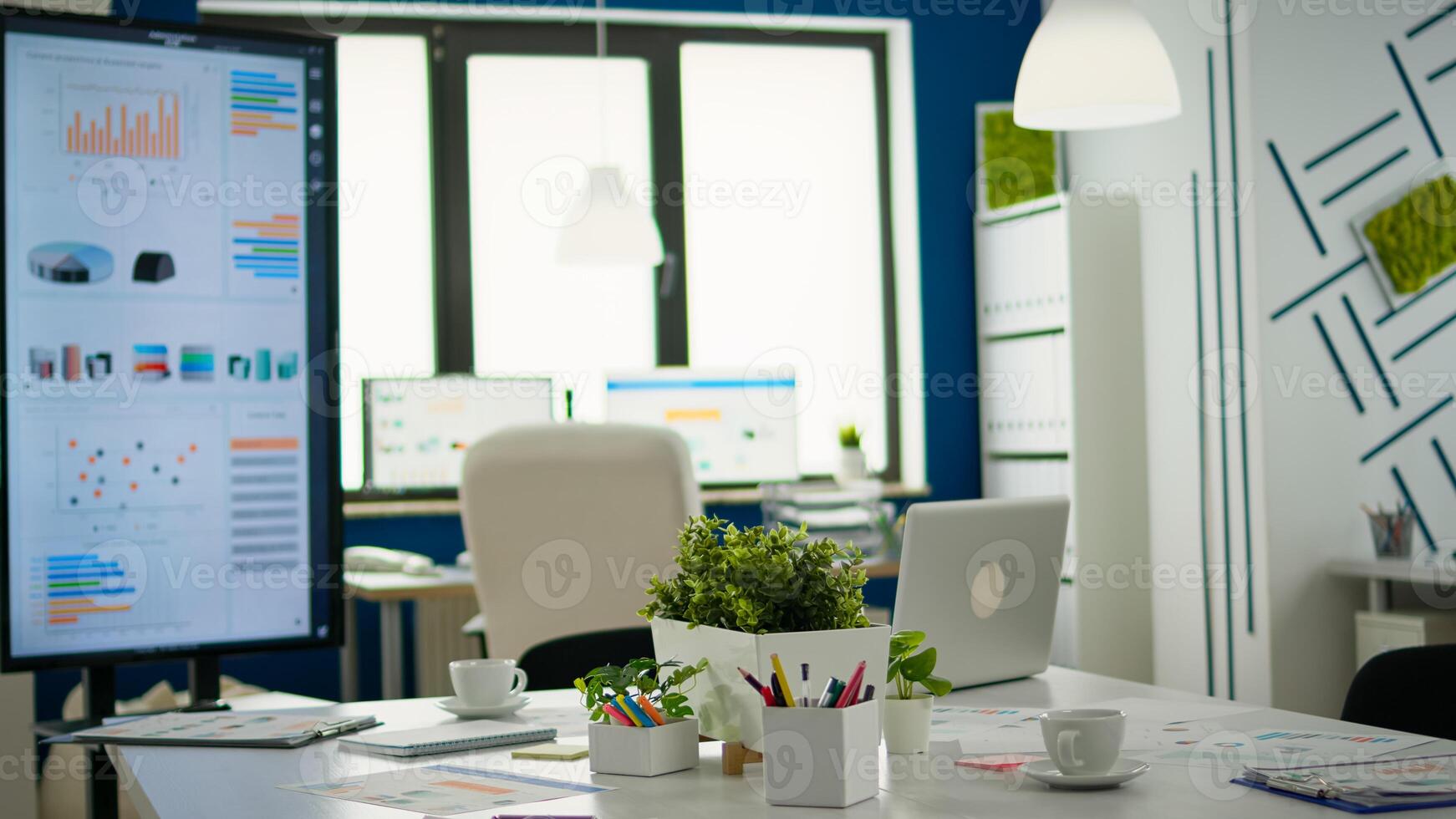 Brainstorm area in business center with nobody in it, shot of empty room with modern furniture, white shelves and blue wall. Modern business meeting zone interior with conference table and white chair photo