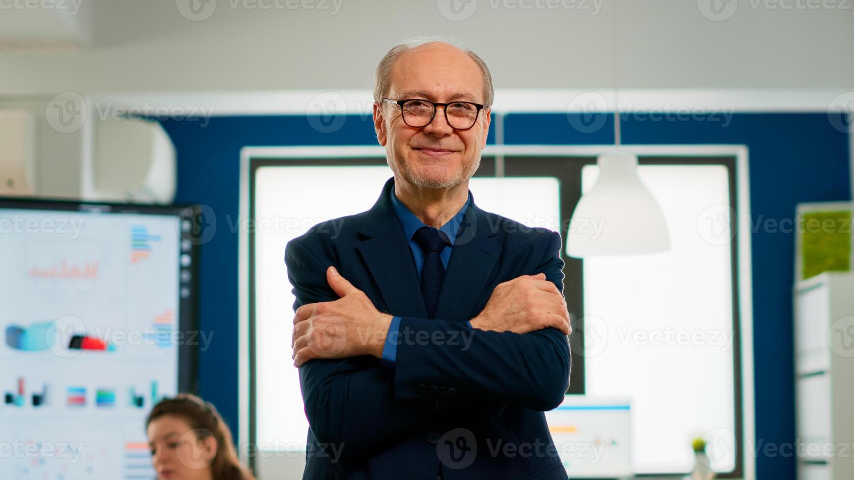 Elderly successful businessman entrepreneur standing looking at camera crossing arms and smiling. Manager working in professional start up financial business, modern company workplace ready for meeting photo