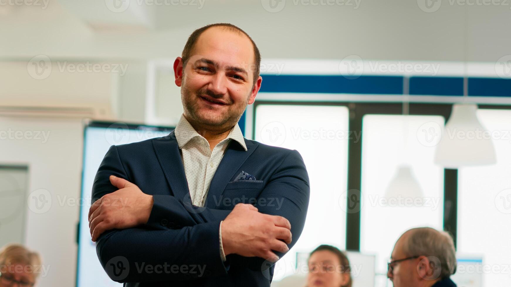 Young man project manager smiling in front of camera standing in brainstorming room, preparing for meeting with partners. Businessman working in professional start up financial business ready for conference photo