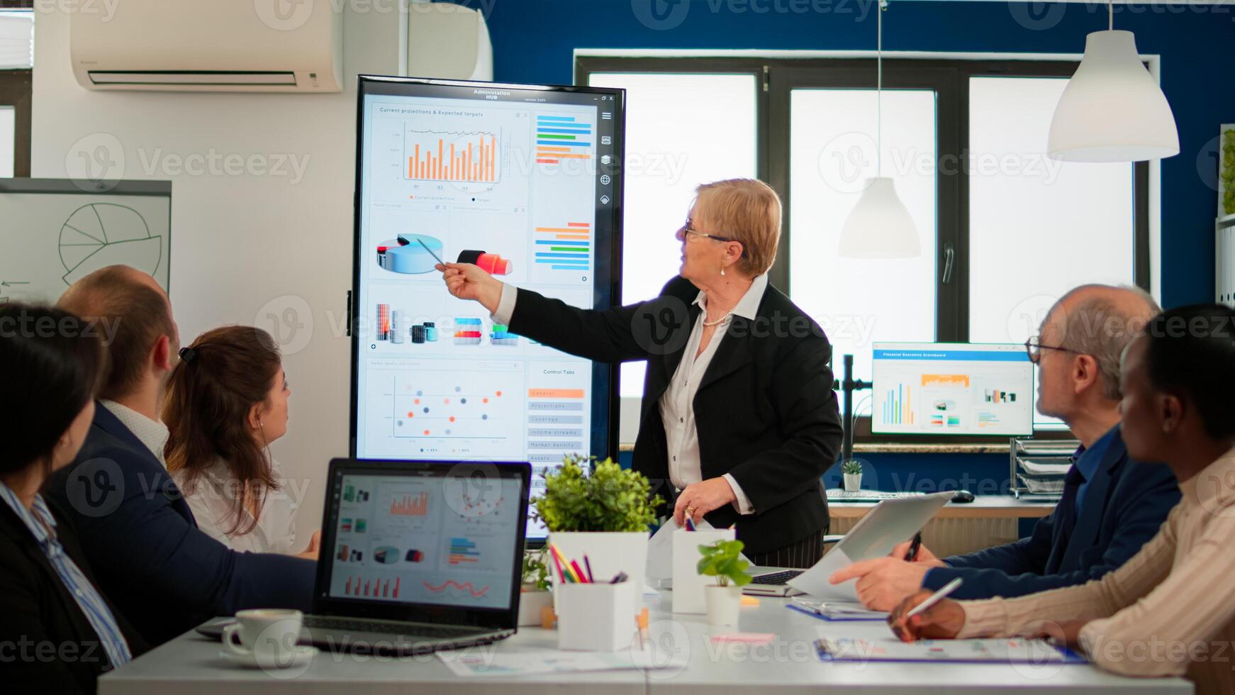 Experienced senior woman CEO CTO of start up company sharing financial reports project strategy briefing diverse group of investors. Multiethnical businesspeople working in professional startup financial company during conference photo