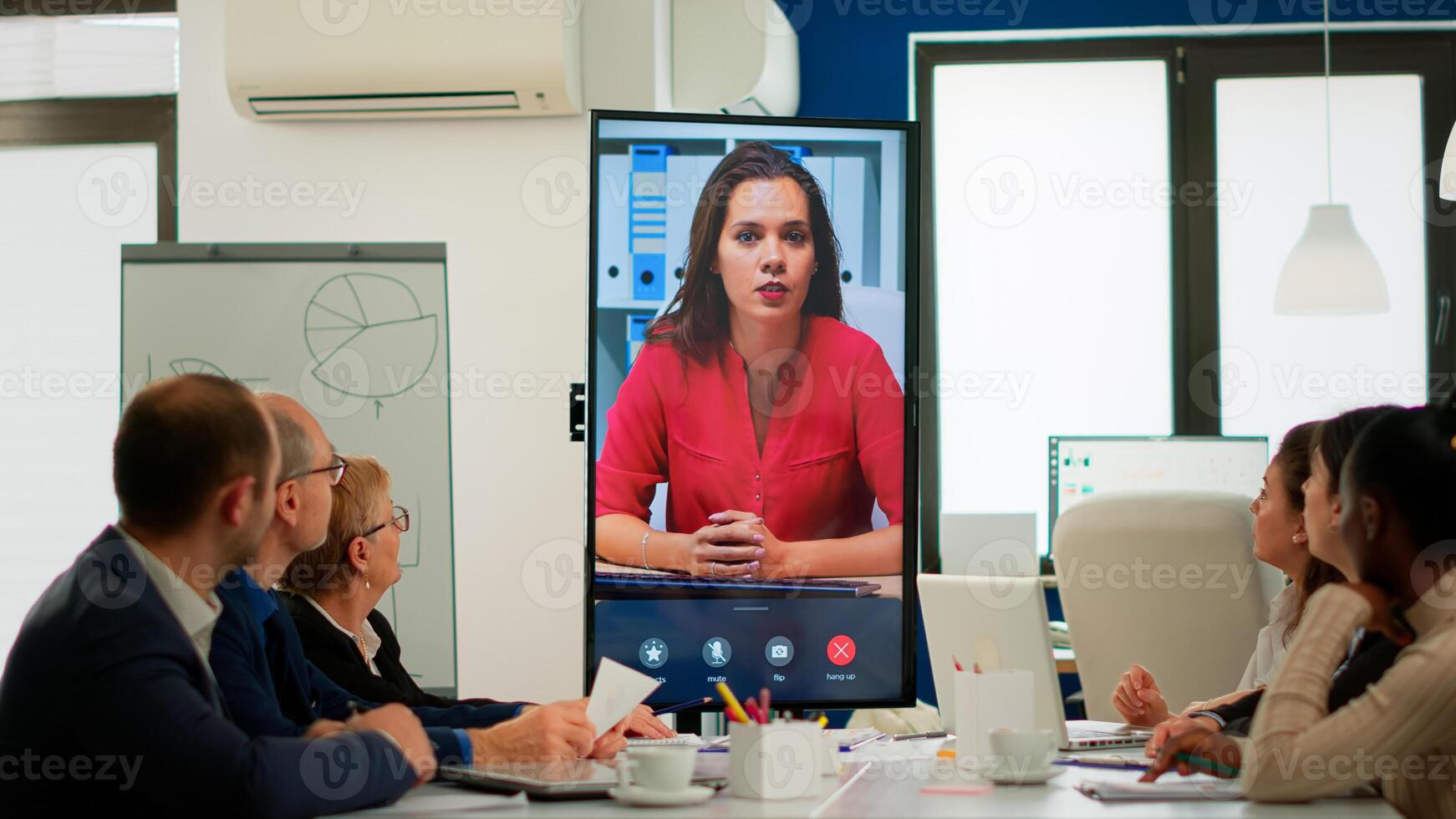 Diverse executive team meeting at conference call looking at huge display. Business people talking to webcam, do online conference participate internet brainstorming, distance office discussion photo