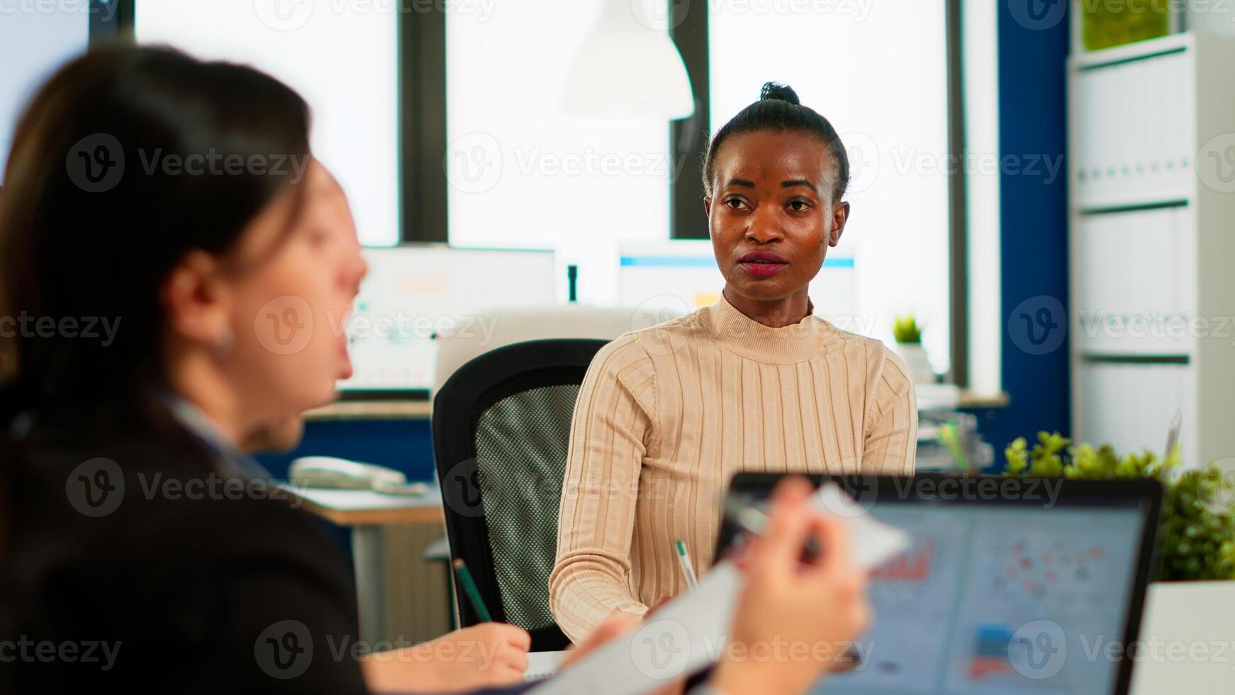 Confident african leader negotiating with business group explaining contract benefits at formal board meeting consulting corporate clients presenting commercial offer sitting at conference office table photo