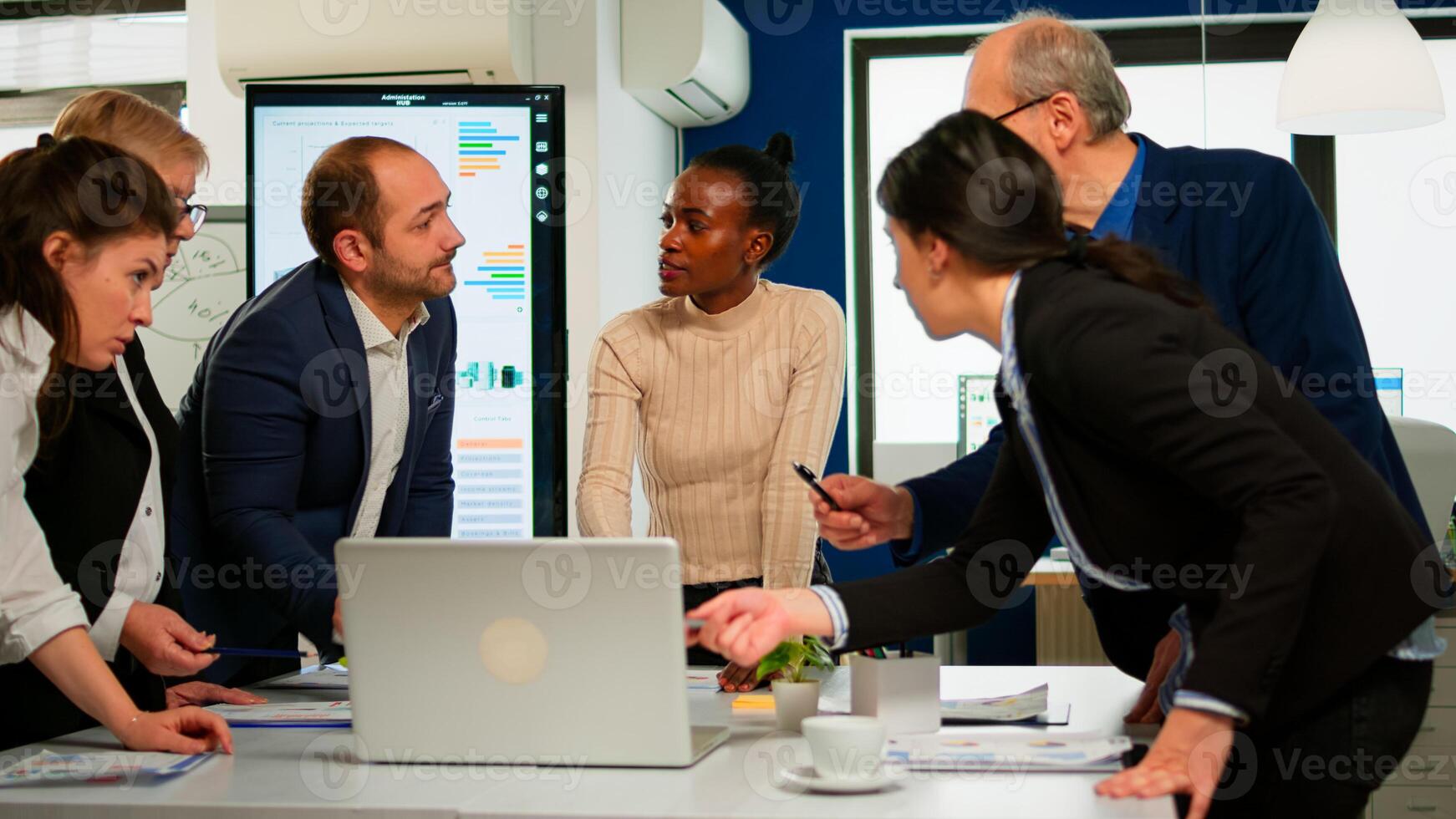 International business team talking to african woman mentor discussing company development plan standing at broadroom. Black leader explainig project strategy to diverse multiracial corporate group photo