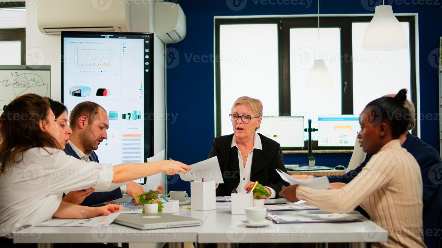 Start up team meeting with company leader planning financial strategy, analysing reports sharing paperwork. Colleagues working in office at conference table in startup management company photo