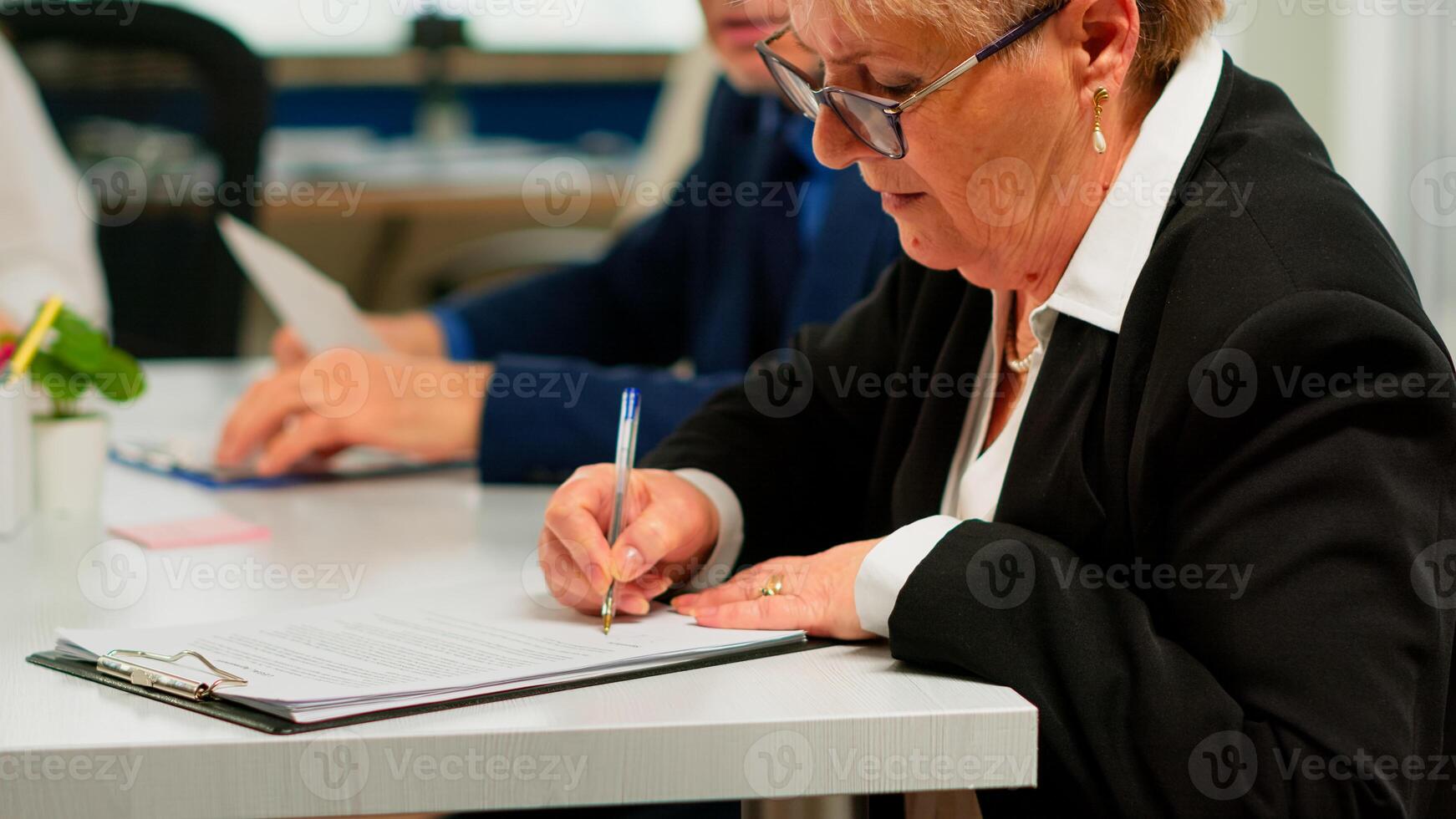 Busiess partners discussing new project for company evolution, senior manager woman checking tasks on clipboard and signing new contract. Executive director meeting shareholders in start up office photo