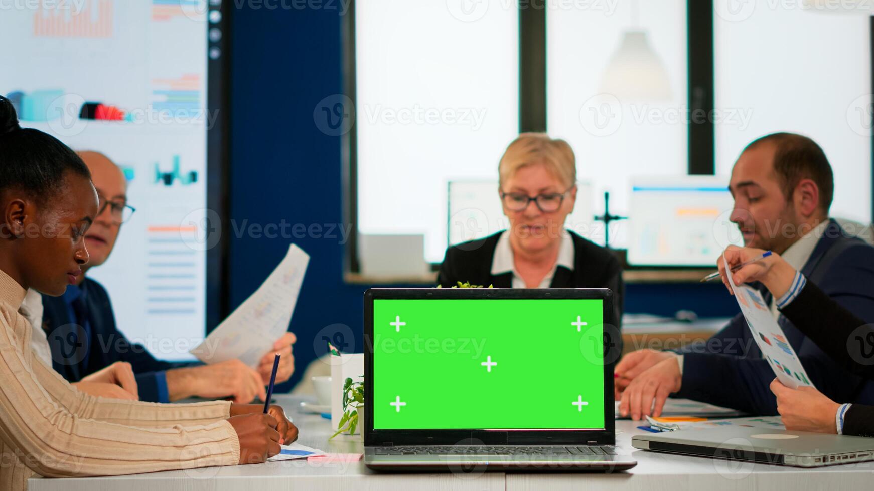 Group of business people discussing company plan with mockup laptop in front of camera, pc ready for financial project presentation placed on desk. Leader using green screen pc with chroma key display photo