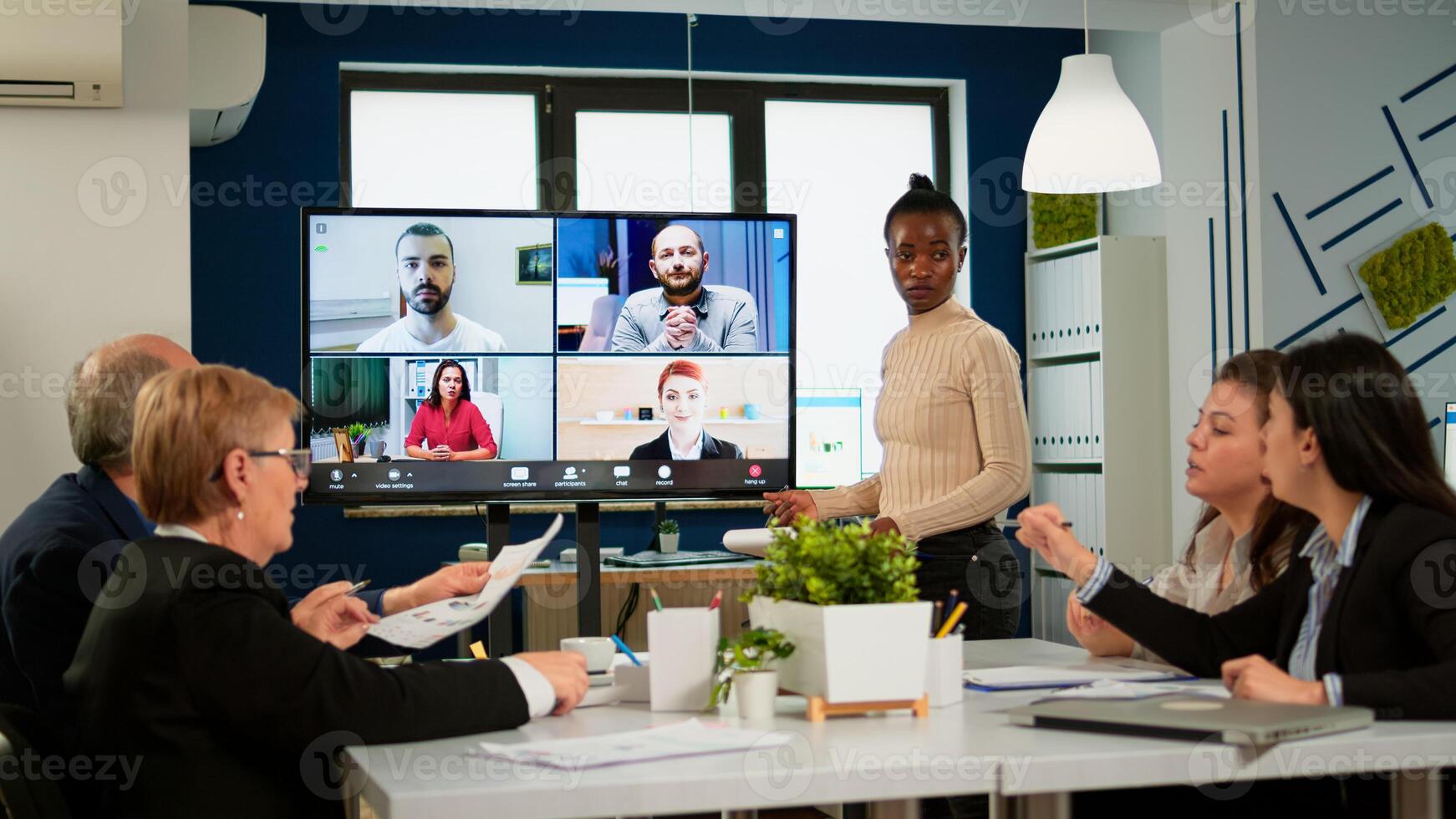 Black manager woman talking with remotely colleagues on call at tv screen, presenting new business partners. Confident businesswoman talking to web cam streaming webcast training, doing online conference call photo