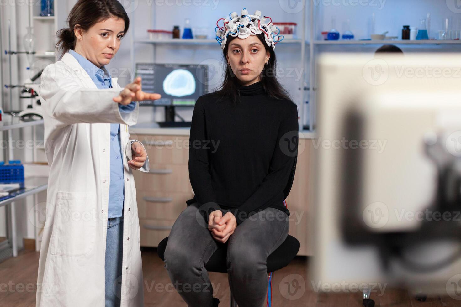 Doctor researcher EEG headset analyzing patient's evolution after treatment against disease of nervous system. Team of scientists working late night in neurological research laboratory. photo