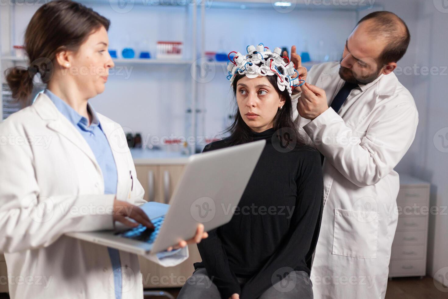Expert medic in neuroscience developing brain experiment holding laptop explaning to woman side effects of nervous system treamtment. Team of scientists working in neurological research laboratory. photo