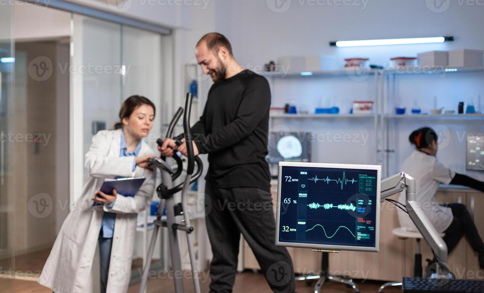 Team of medial researchers monitoring vo2 of man performance sports wearing mask running. Lab science doctor measuring endurance of sportsman while ekg scan runs on computer screen in laboratory. photo