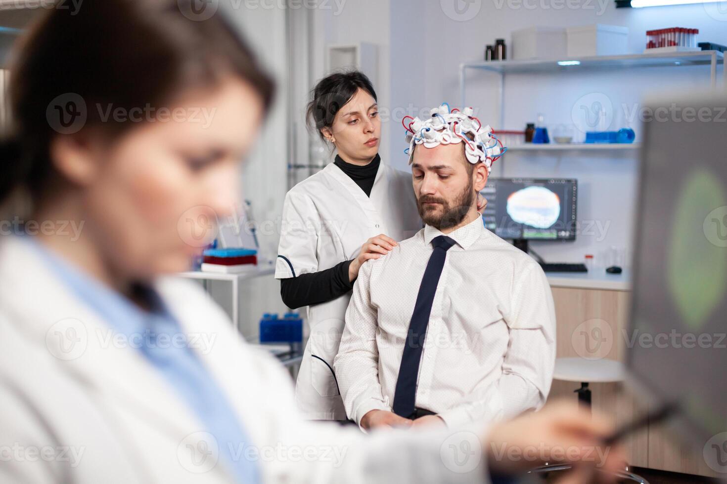 Man patient wainting for brain experiment with headset in research lab while scientist is making adjusting, inovations high tech clinic. Neurologist study nervous system. photo