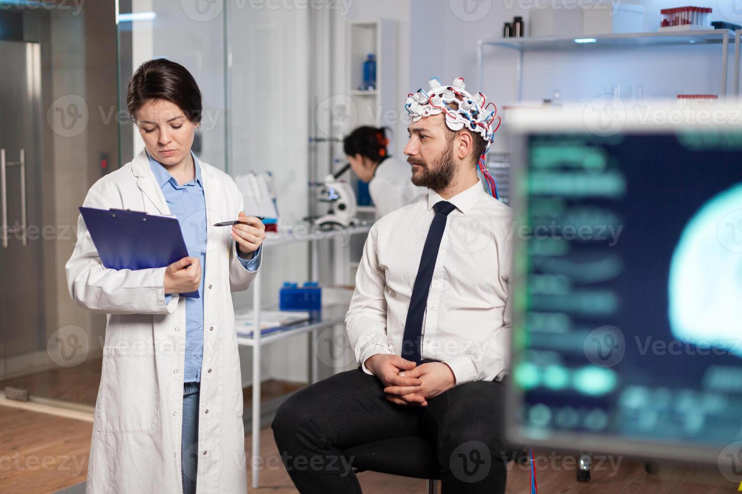 Medical doctor talking about symptoms of disease during investigations using high tech brainwave scanning headset. Researcher analysing health status of man patient, brain functions, nervous system. photo