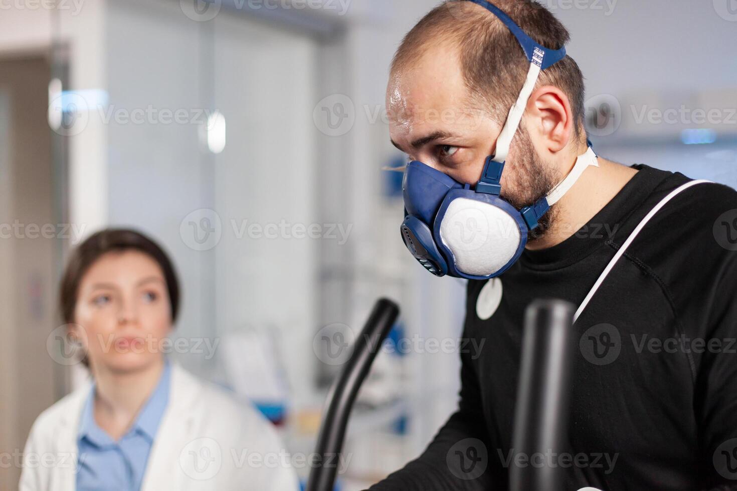 Runner athlete testing cardio heart rate in sport endurance laboratory with mask and electrodes on body, vo2. Sportman training with sensor on cross research. photo