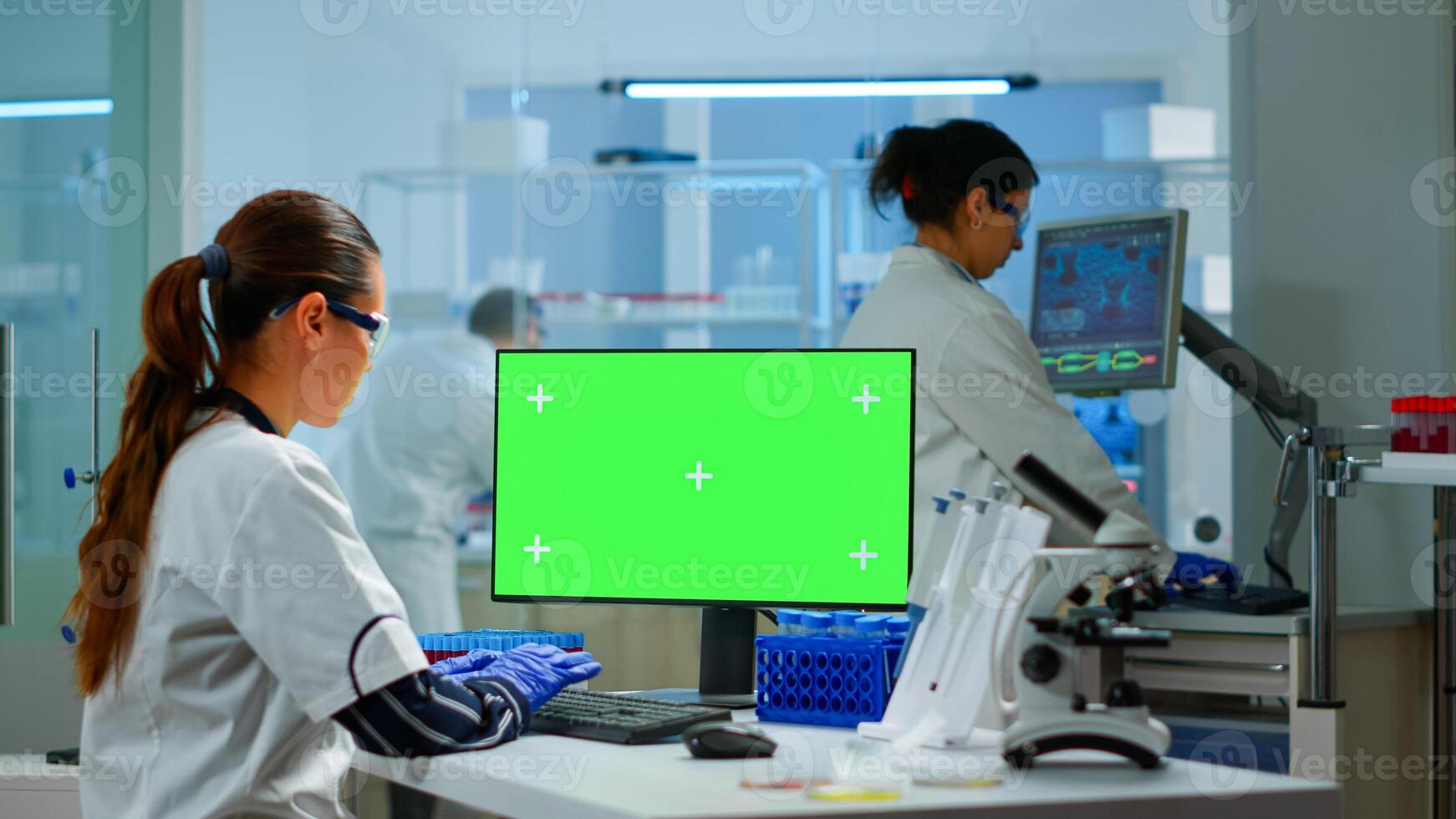 Medical research scientist working on pc with green screen mock up template in applied science laboratory. Engineers conducting experiments in background, examining vaccine evolution using high tech photo