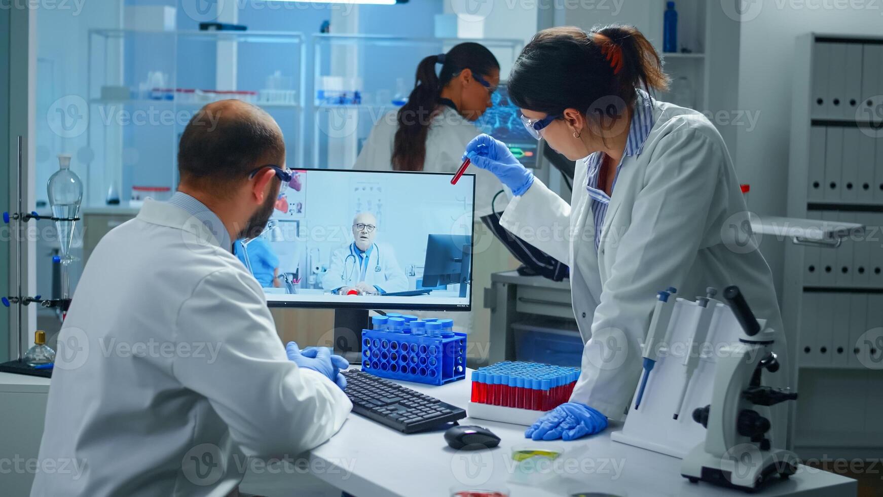 Lab technicians talking on call with professional chemist doctor explaning vaccine reactions, woman nurse showing blood sample on web cam, during virtual meeting in medical research laboratory photo
