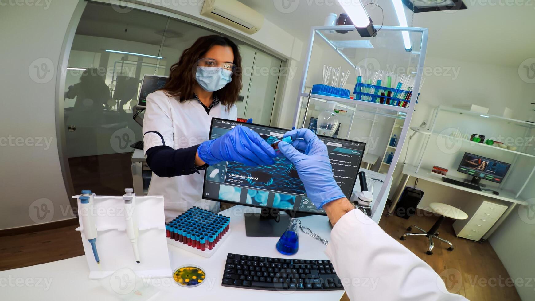 Chemist doctor holding test tube with blood sample talking with researcher, entering datas in pc. Team of scientists analysing vaccine evolution using high tech researching diagnosis against covid19 . photo