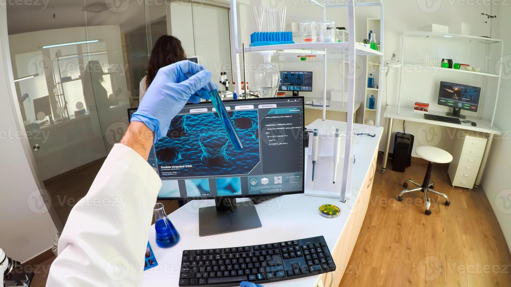 FPV of biologist doctor checking DNA image typing on pc, while colleague bringing tubes with samples, Scientists examining vaccine evolution in medical lab using high tech for scientific research. photo