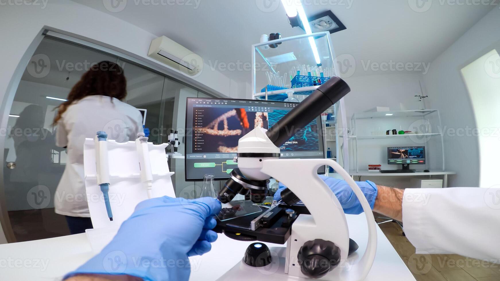 FPV of medical scientist looking under microscope, analyzes petri dish sample in equipped lab. Medical stuff examining vaccine development using high tech researching treatment against covid19 virus photo