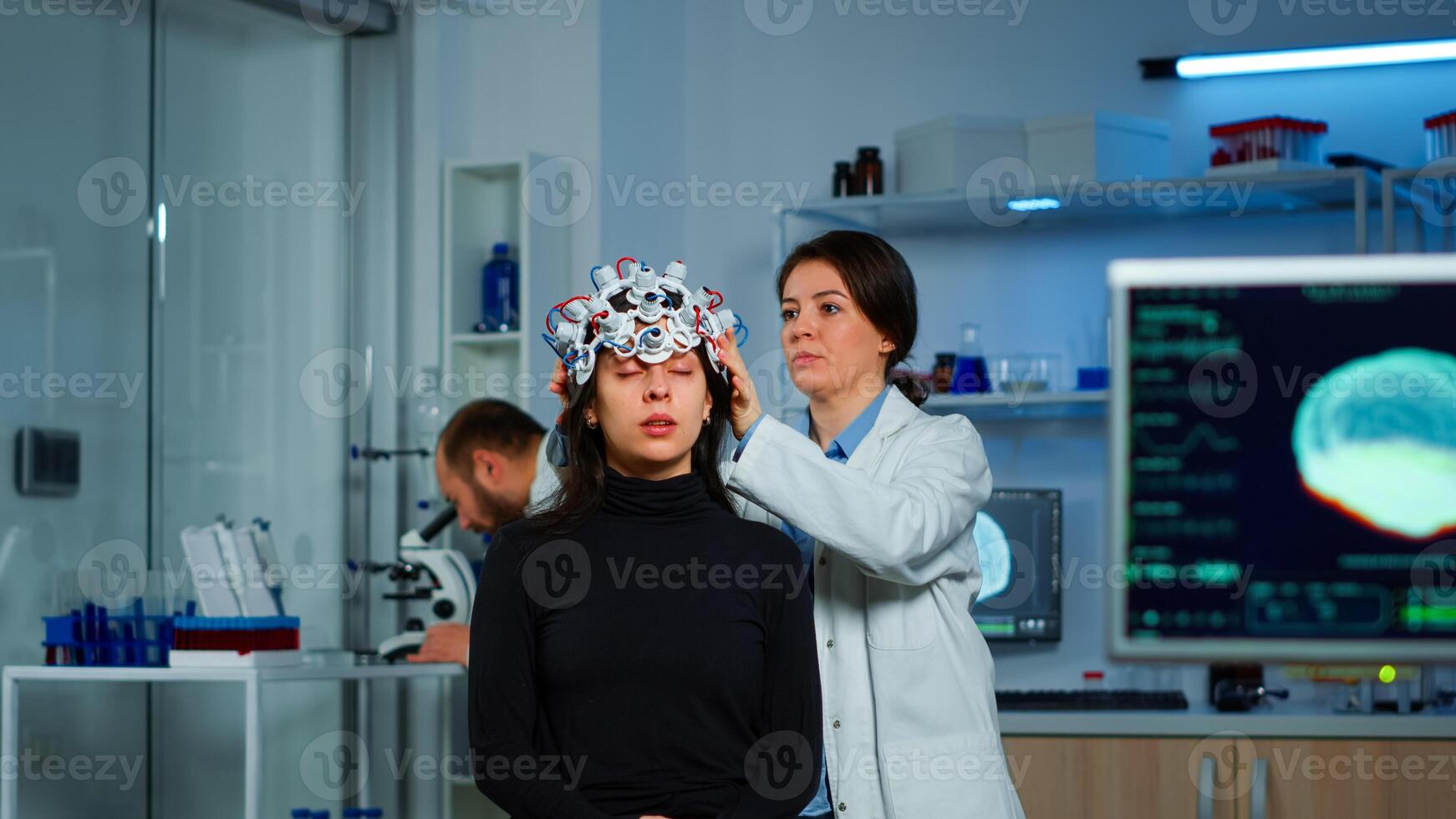 Asistance of neurological doctor putting eeg headset on patient head scaning brain functions, descovering diagnosis of disease. Team of scientists researchers working late night in neurology clinic photo