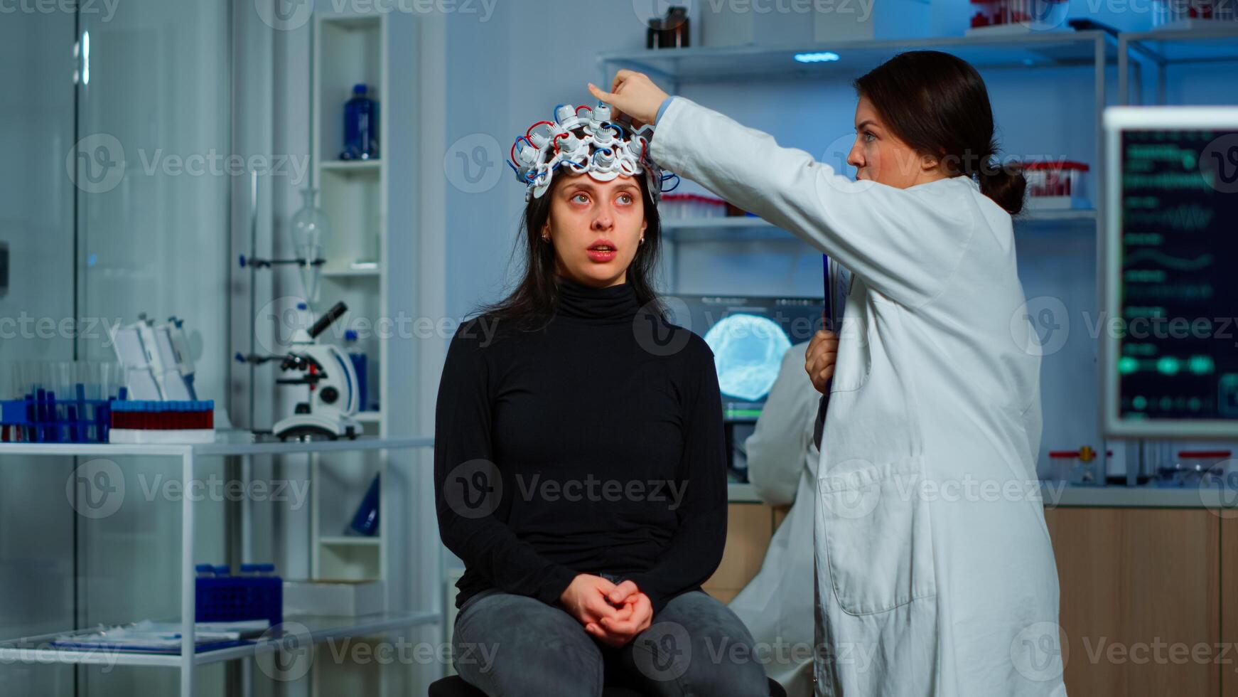 Doctor researcher adjusting EEG headset analyzing patient's evolution after treatment against disease of nervous system. Team of scientists working late night in neurological research laboratory photo