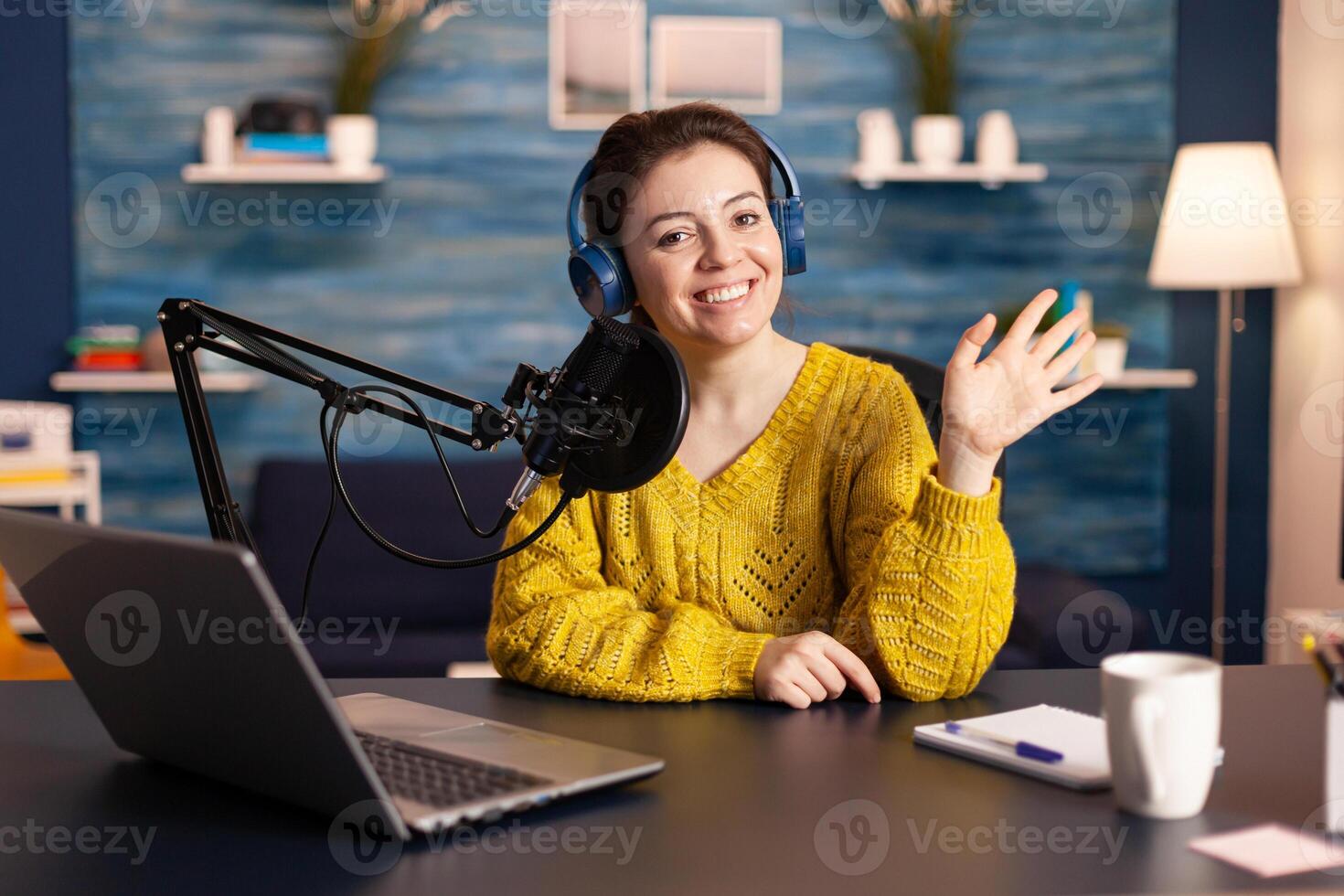 Social media influencer smiling at camera sitting in home studio ready for streaming new podcast. On-air online production internet broadcast show host streaming live content record digital blog. photo
