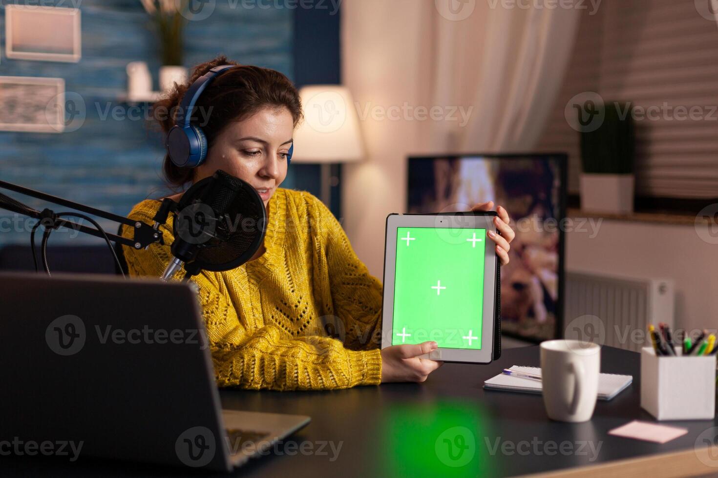 Influencer holding tablet with green screen display recording new podcast series for audience. Broadcast show host streaming live content for social media using mochup, chroma key, izolated desktop. photo