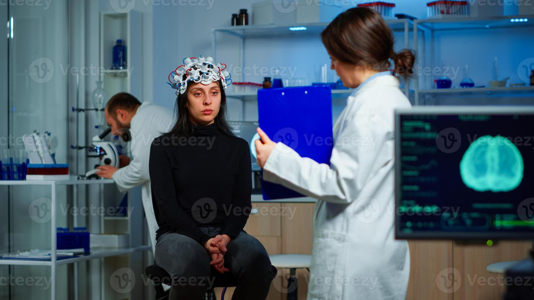 Neuroscience doctor holding clipboard showing treatment against brain disease to patient with eeg headset. Woman sitting in neurological scientific laboratory treating nervous system dysfunctions photo
