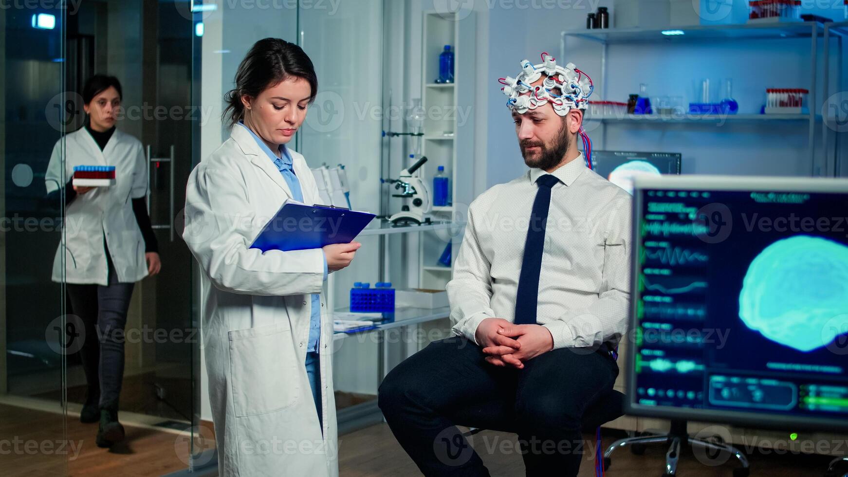 Medical doctor talking about symptoms of disease during investigations using high tech brainwave scanning headset. Researcher analysing health status of man patient, brain functions, nervous system photo