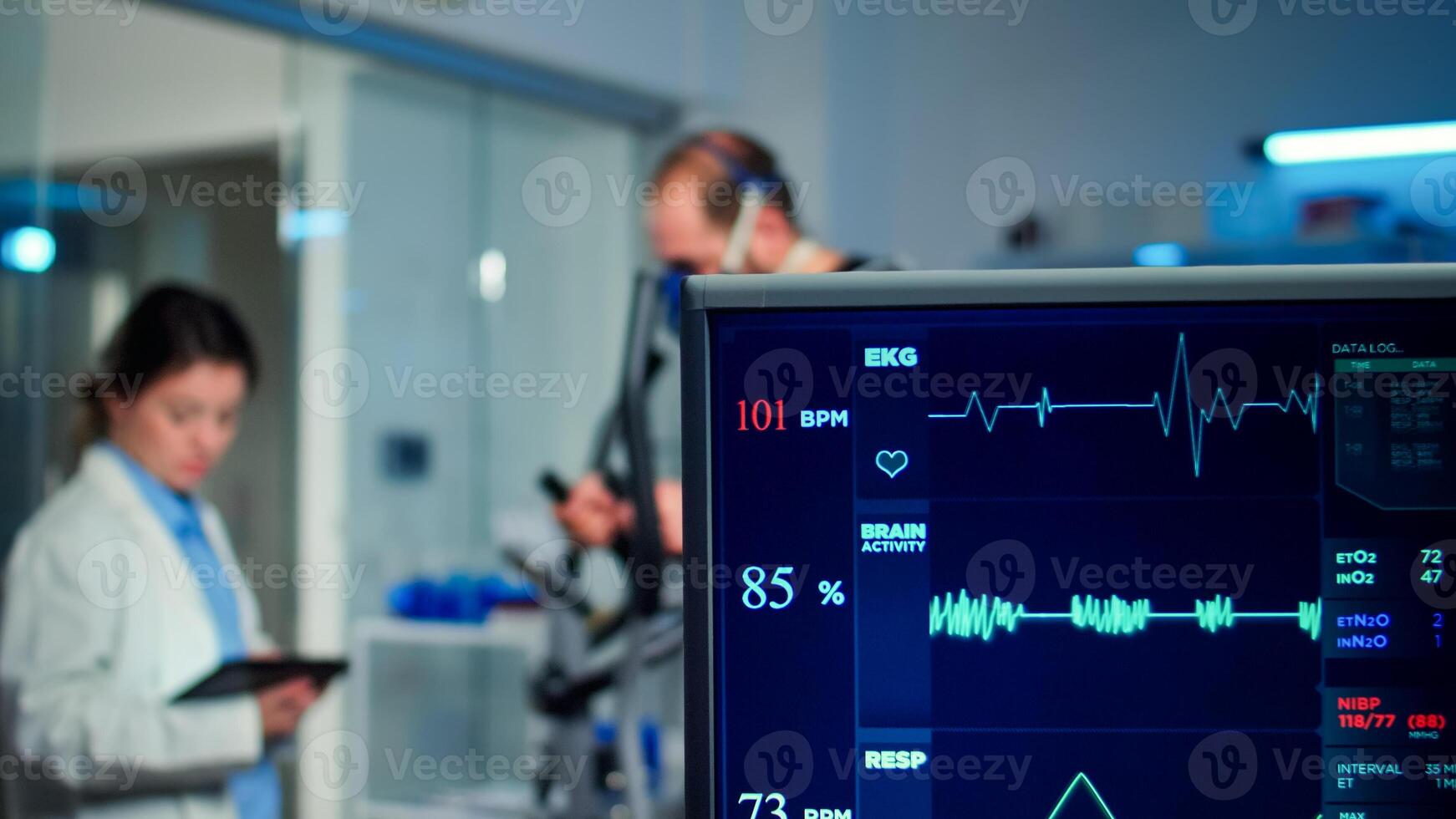 Specialist health supervisor increasing level of exercises measuring muscle endurance of athlete. Medical researcher measuring vo2 of performance sports running with mask on cross trainer in sport lab photo