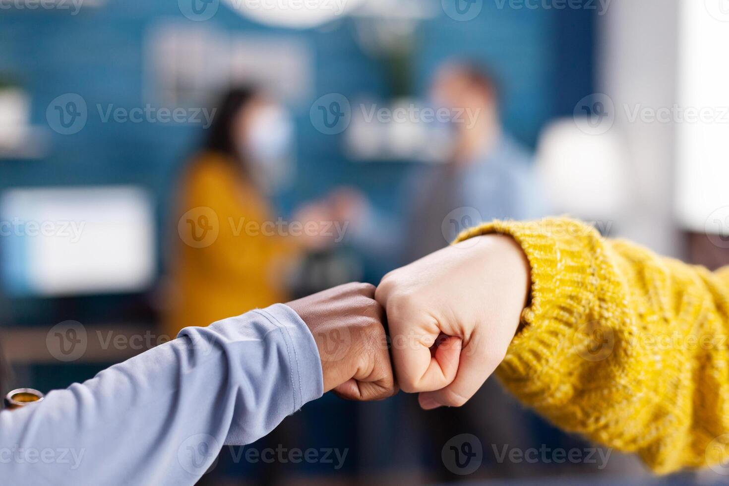 Close up of african woman and friend doing fist bump greeting each other in hme living room keeping social distancing as safety precaution during global pandemic with coronavirus. photo