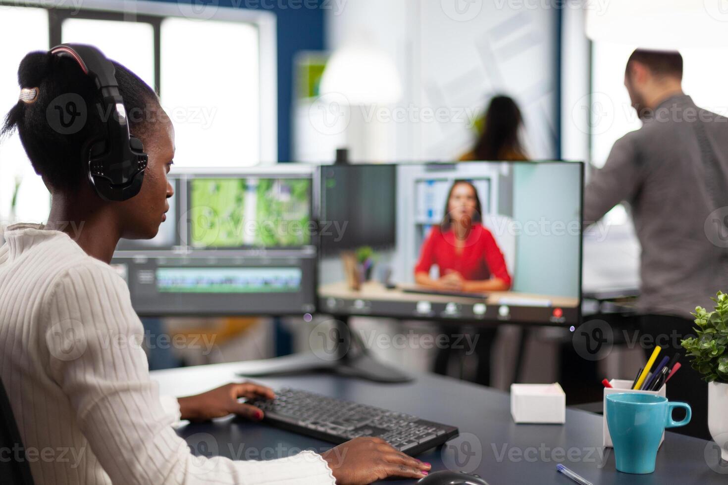 editor in web online conference with project creator on call editing business client work, getting feedback on movie using post production software on two monitors in start up office photo