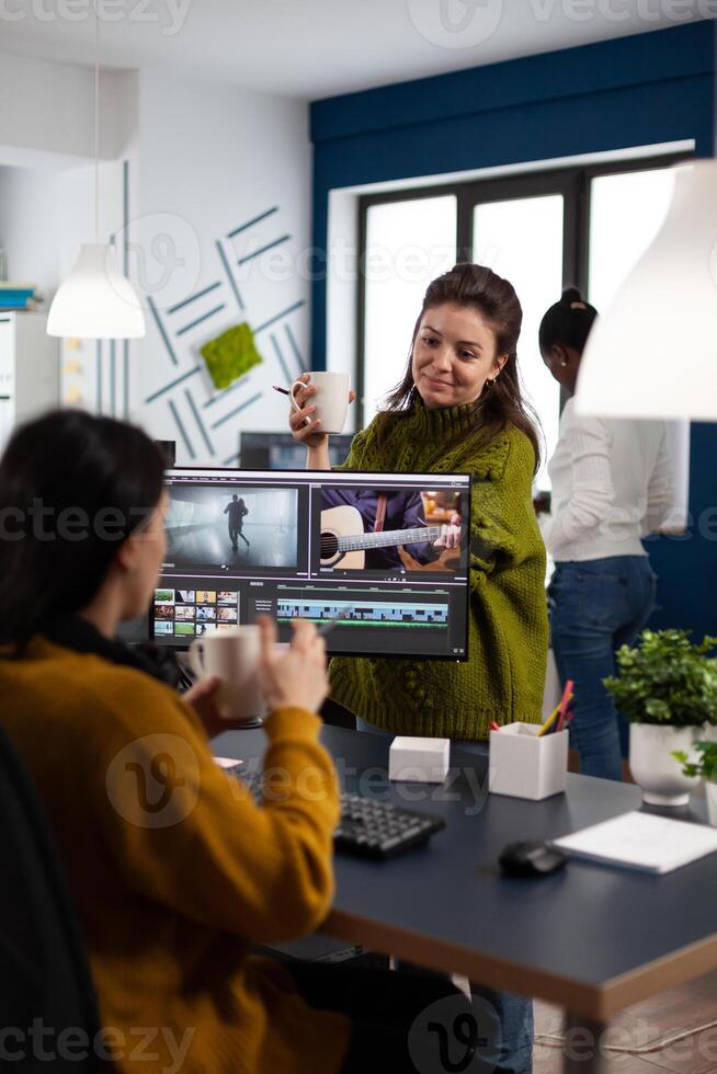 Women videographers editing project creating multimedia content, team of bloggers working in modern creativity office studio. Manager explaning to colleaque film montage discussing production photo