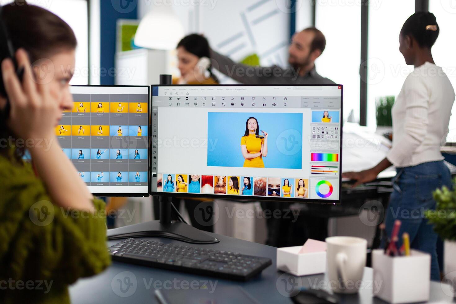 Retoucher woman editor working on computer with two monitors and stylus pencil in photo editing software sitting in creative agency office. Graphic designer retouching client photos using image app
