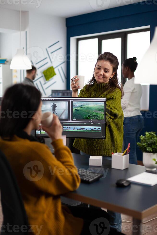 Women videographers editing project creating multimedia content, team of bloggers working in modern creativity office studio. Manager explaning to colleaque film montage discussing production photo