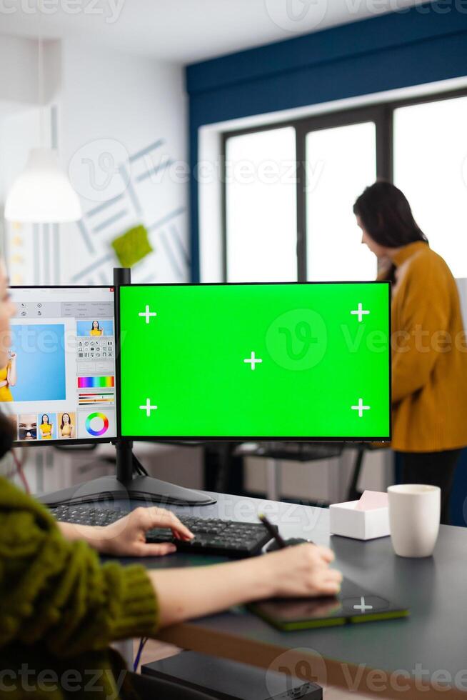 Photo artist retoucher editing assets in digital retouching program working in production agency studio. Photographer woman looking in computer with green screen, chroma key mockup isolated display.