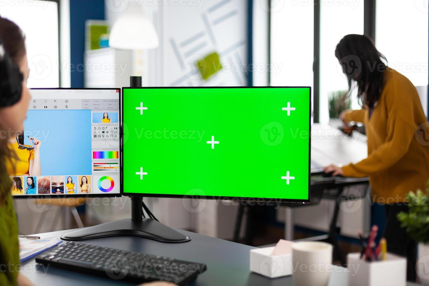 Woman digital artist working editing creative photo using greenscreen, chroma key isolated display of computer. Photographer retoucher creator doing portrait retouching in multimedia company