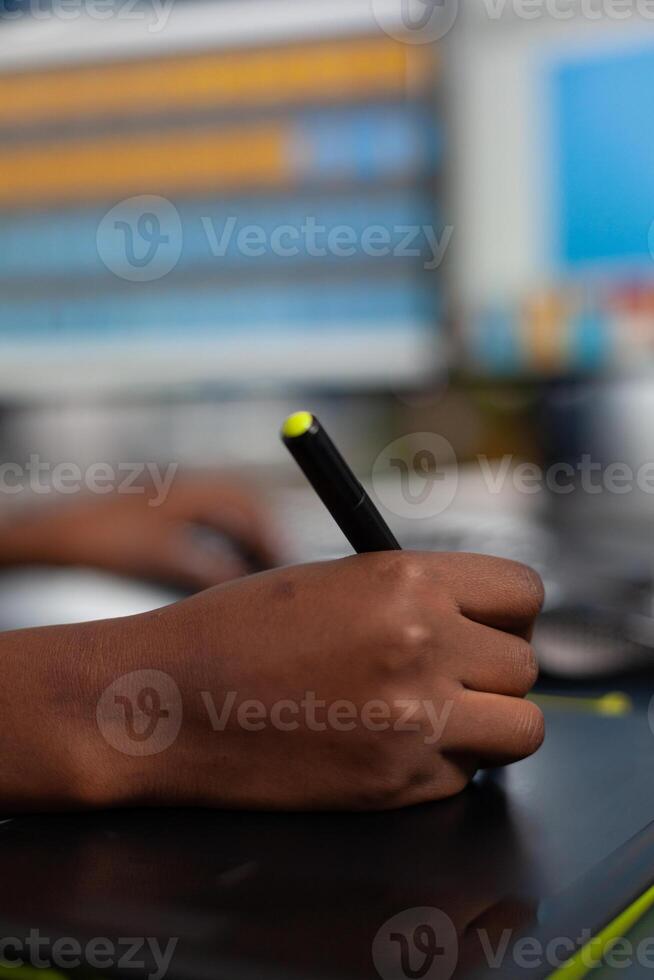 Close up of black designer editing customer client image with stylus pencil, drawing on graphics tablet. Hand of african american woman editor photographer retouching assets working in creative production company office photo