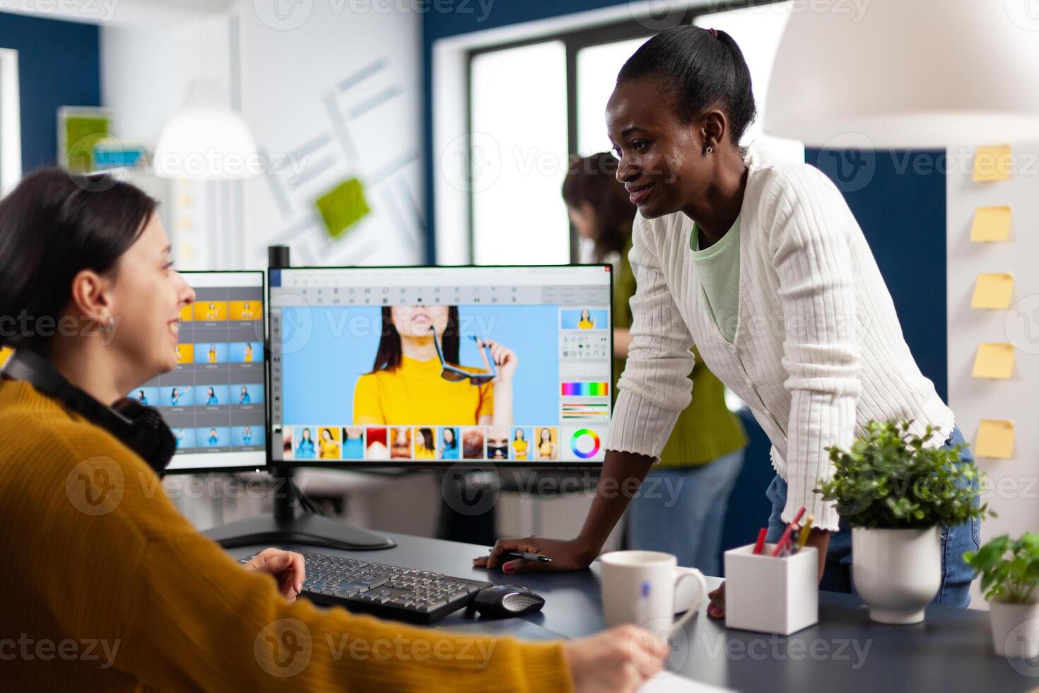 African art company director consulting retoucher colleague, retouching portrait, photo editing software in creative agency. Editor working with color grading assets using graphic tablet with stylus pen