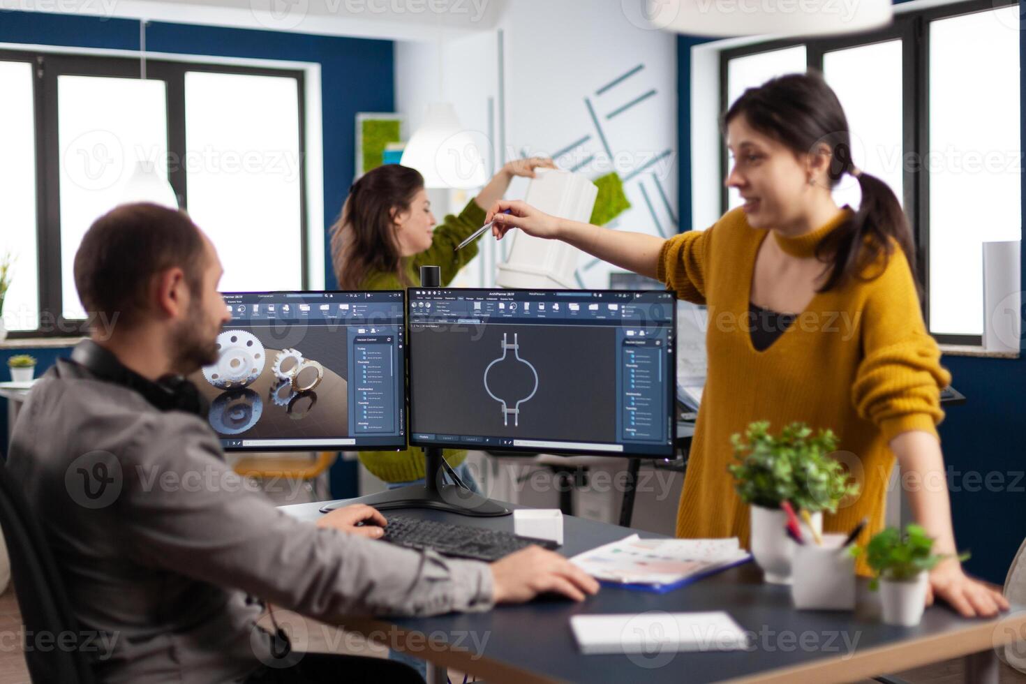 Excited mechanical teamwork laughing and discussing about manufacturing new product, taking break. Man technician working at pc, screen shows 3D program made with CAD software, using computer photo