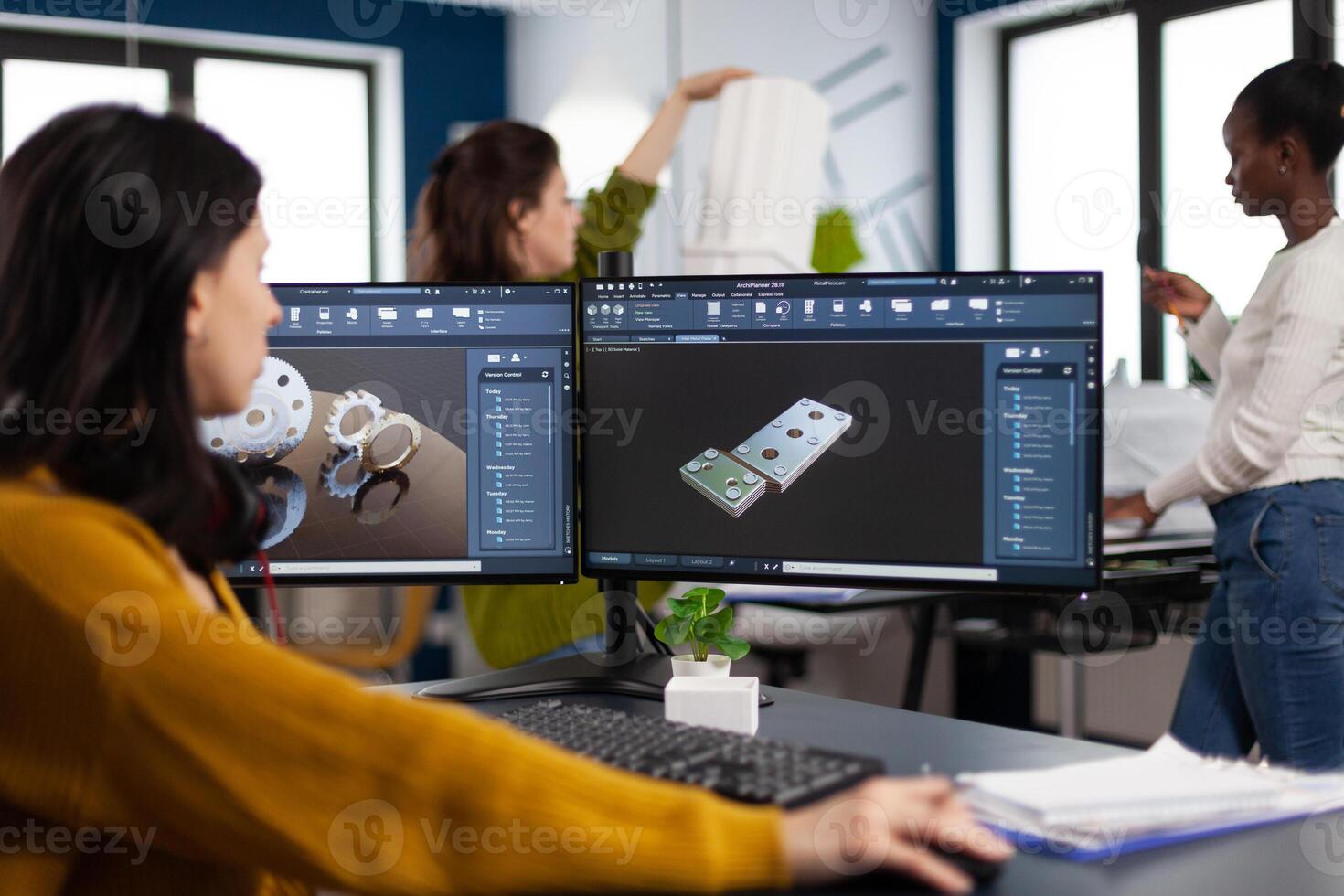 Industrial engineer woman working at pc with two monitors, screens showing CAD software with 3D architecture prototype of gears mechanical piece. Entrepreneur working in creative construction office photo