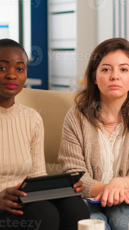Start up company team talking during meeting sitting on couch listening and explaning to remote manager company strategy. Multiethnic coworkers discussing about startup financial company. photo