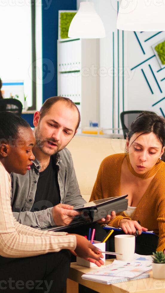 International business team talking to african woman mentor discussing company development plan. Black leader explainig project strategy to diverse multiracial corporate group modern start-up office photo